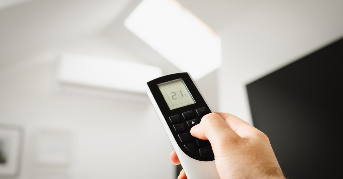 Technicien intervenant sur une unité de climatisation devant une maison de la région lyonnaise